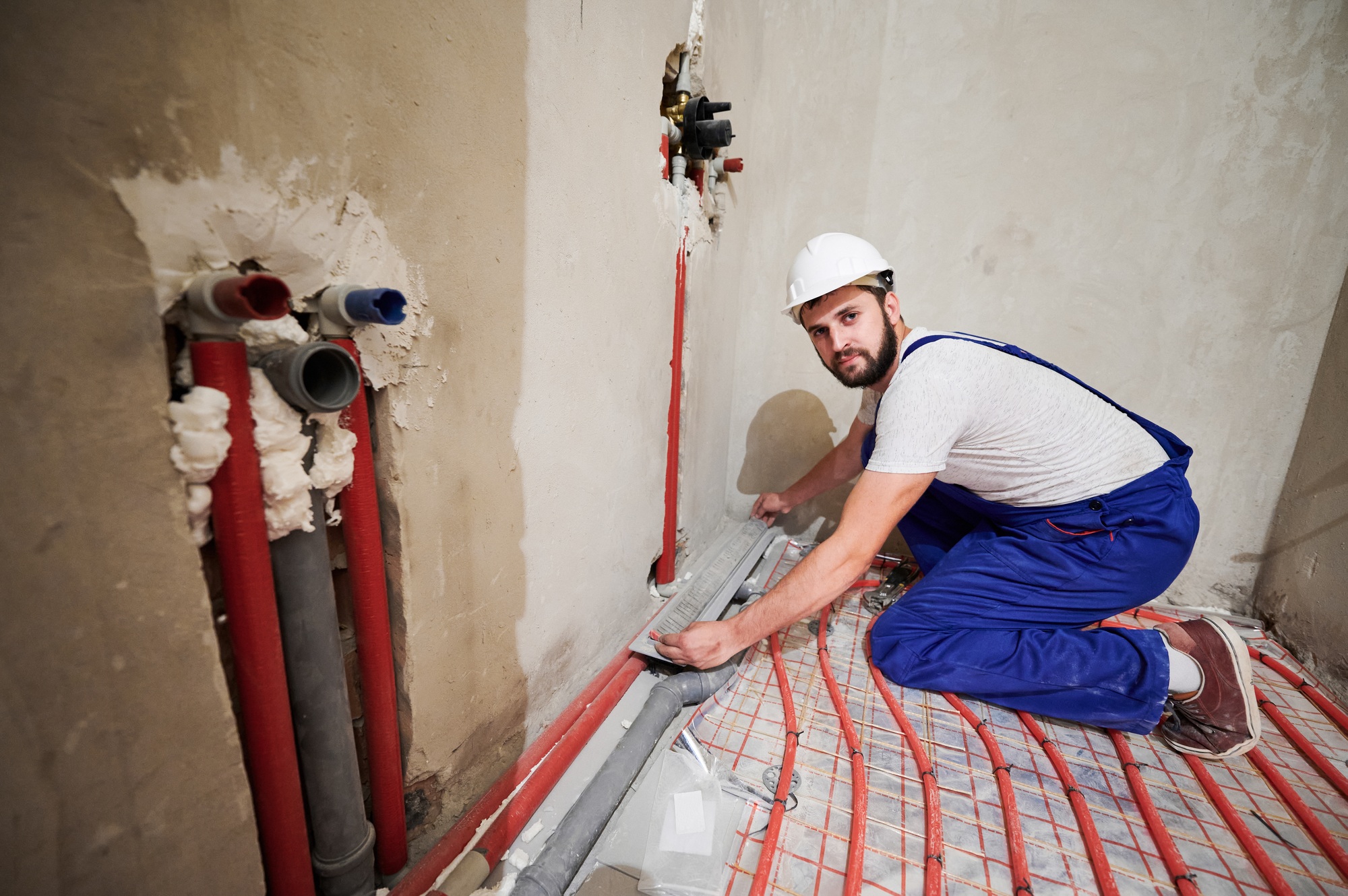 Male worker installing underfloor heating system in apartment.